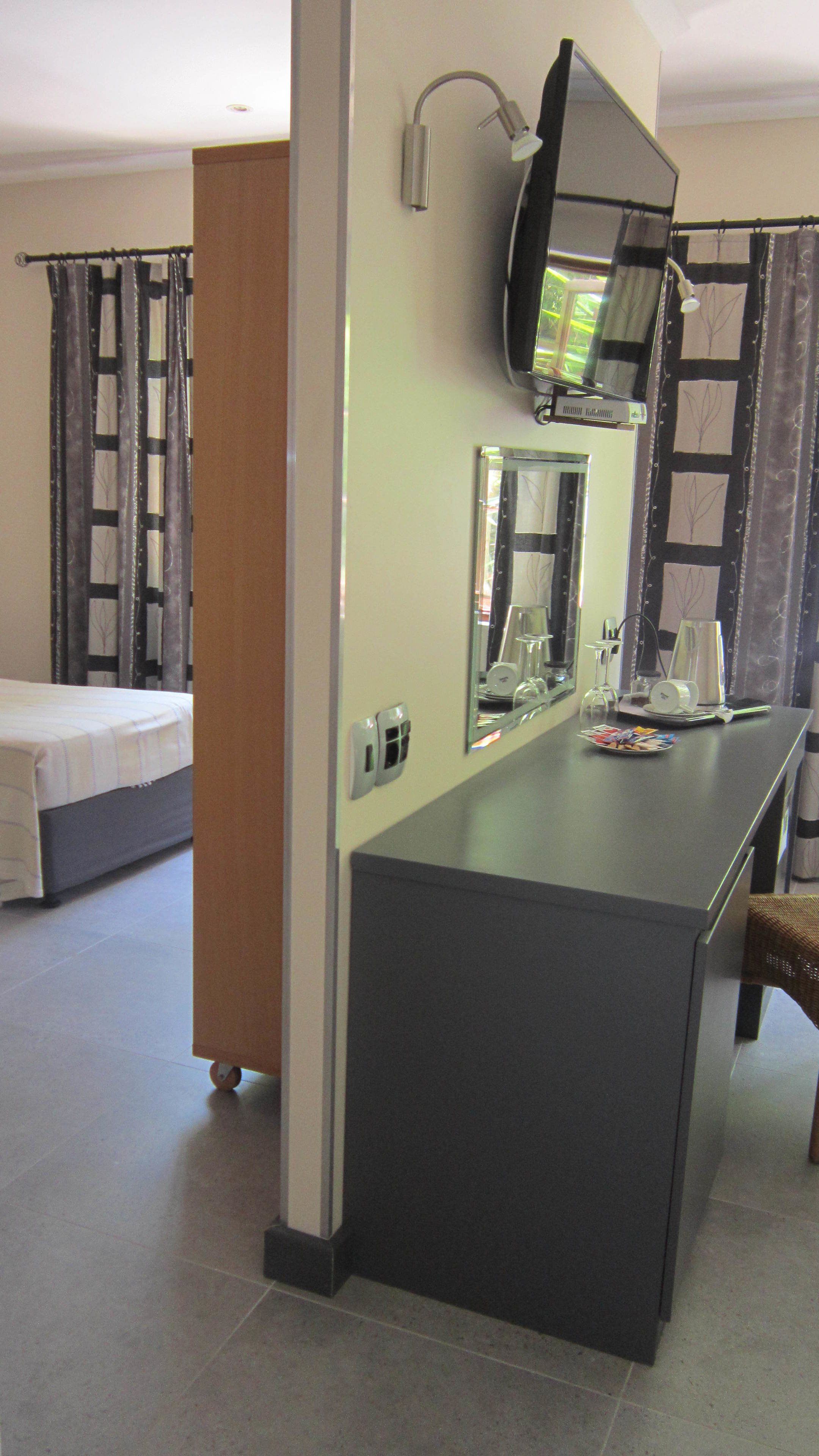A hotel room with a bed, a small sitting area with a chair, a table, and a mirror.