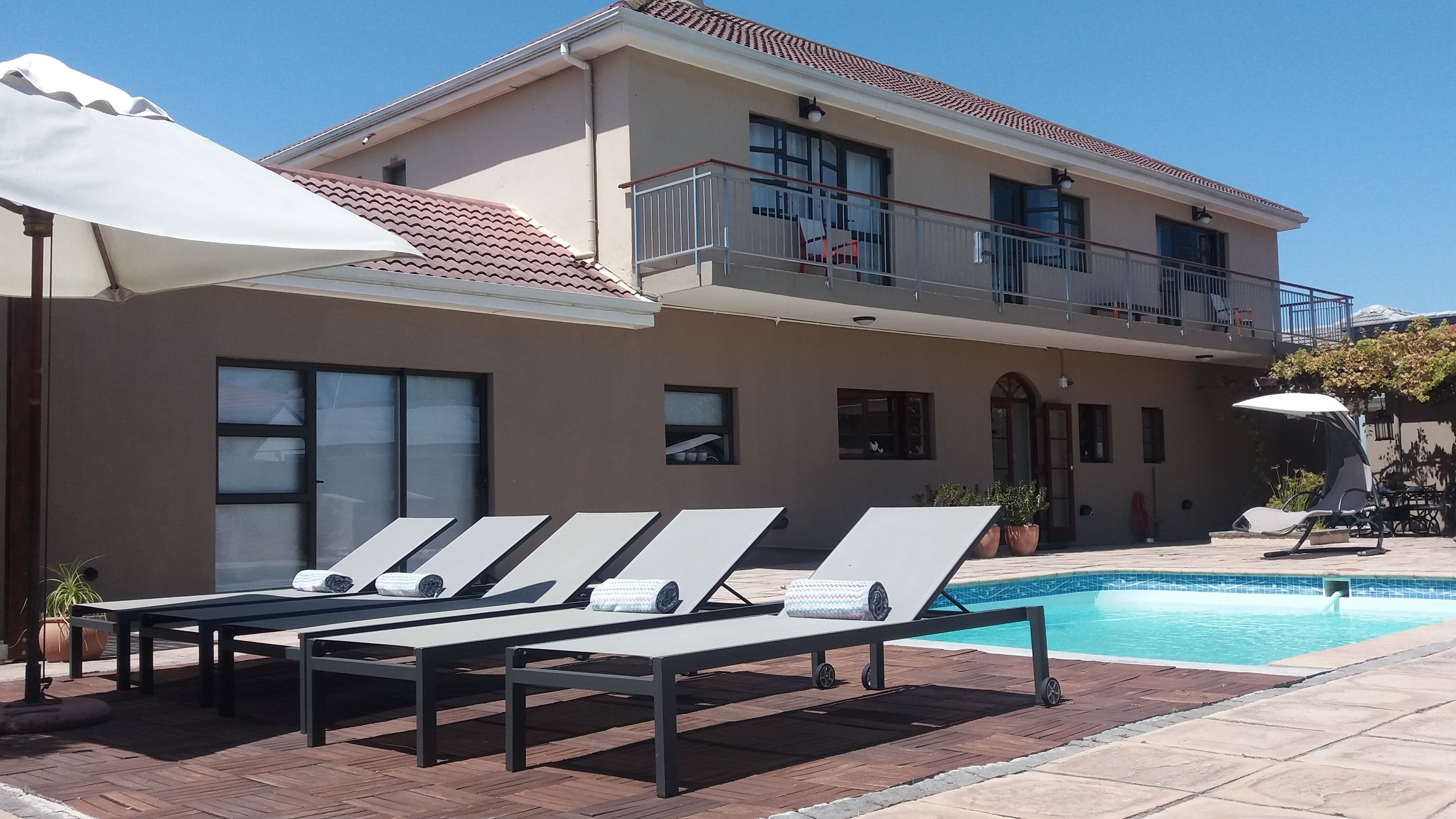 Una piscina al aire libre, sombrillas, tumbonas