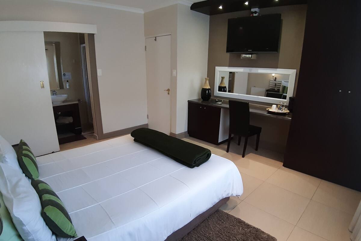 Un dormitorio con cama, escritorio, silla, televisión y baño.