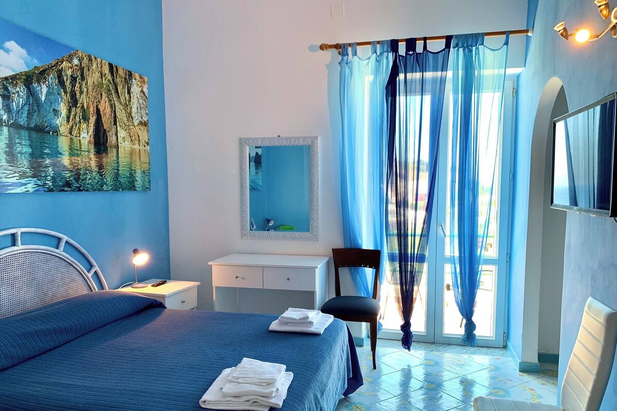 Une chambre à coucher avec un lit, un bureau, une chaise, un miroir et un téléviseur.