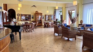 A spacious hotel lobby with a piano, dining area, and comfortable seating. - Hotel Ortensia (Ponza)