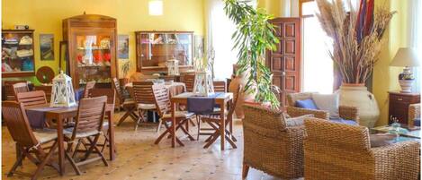 Una habitación amplia con suelo de baldosas, muebles de madera y una planta grande.