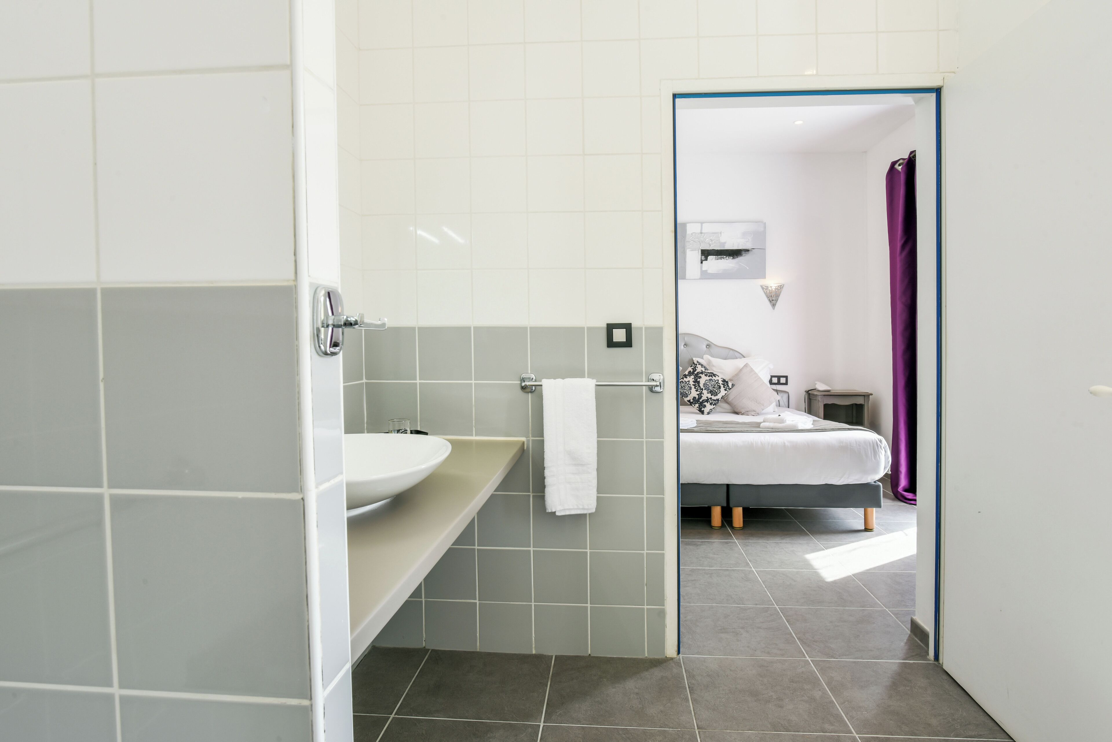 Un baño moderno con un lavamanos blanco, un perchero y una cortina de ducha.