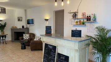 A hotel reception area with a counter displaying menus, a fireplace, seating area, and a wall-mounted TV.