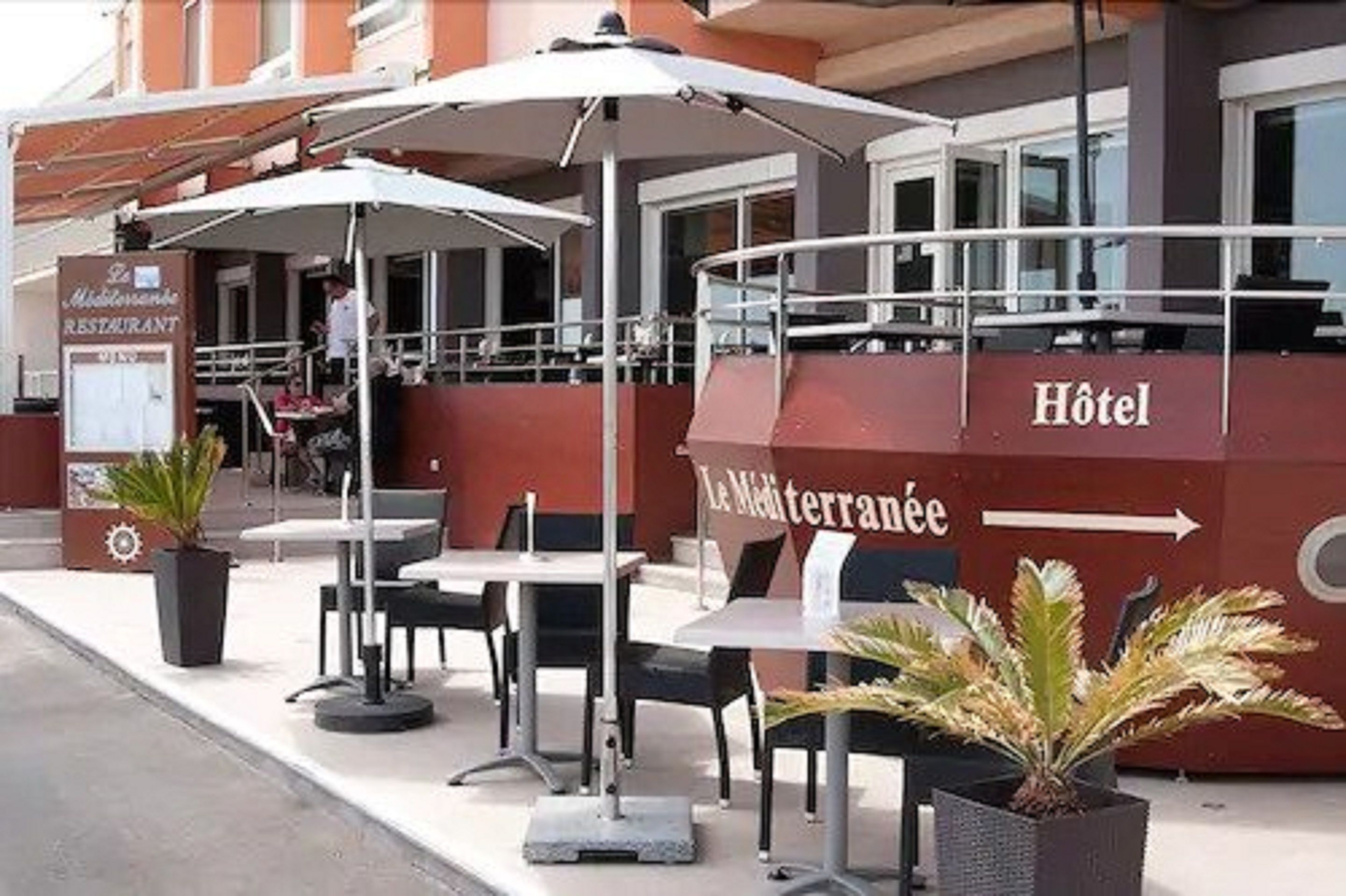 An outdoor seating area with tables and umbrellas at a hotel.
