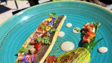A plate of food with a fish fillet, vegetables, and sauce.