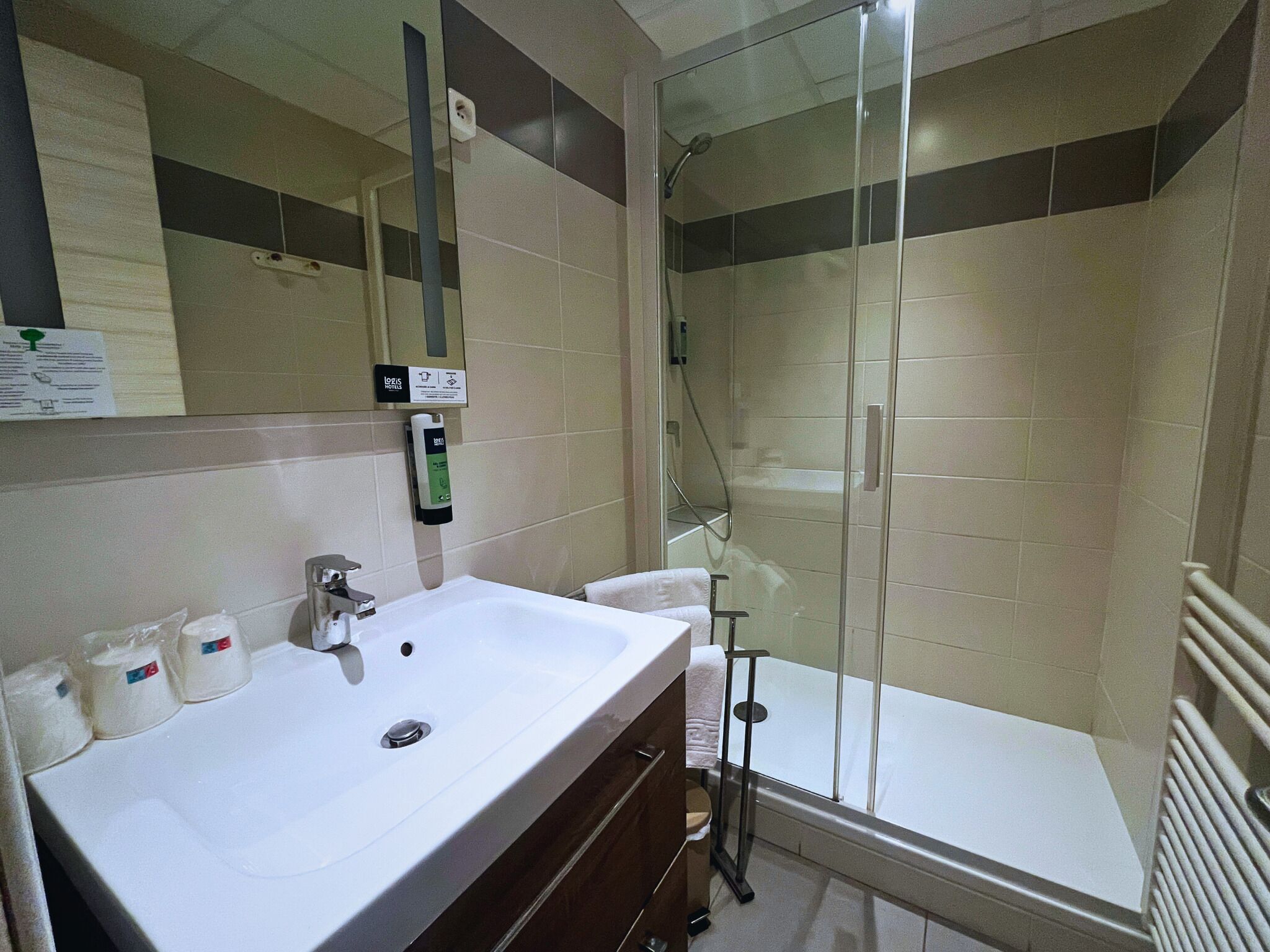 A modern bathroom with a white sink, a glass shower enclosure, and a towel rack.