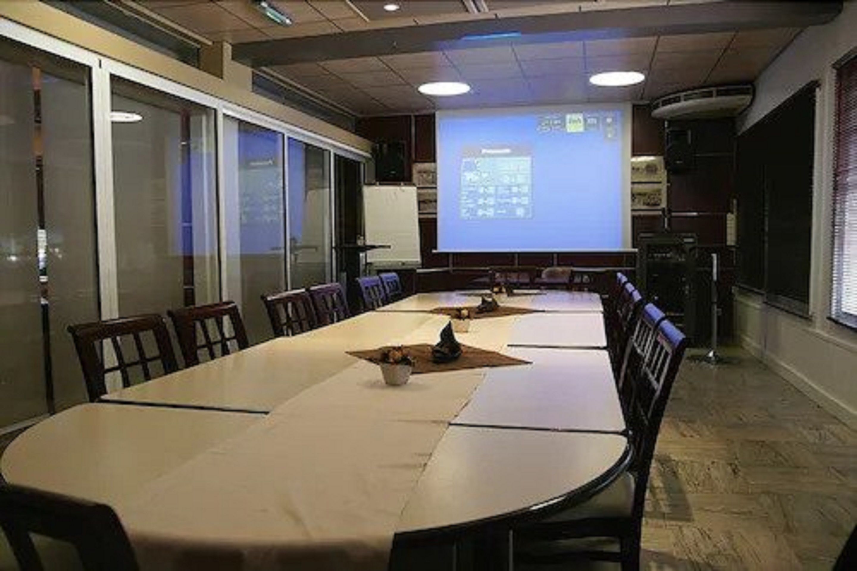 A conference room with a long table and chairs, a projector screen, and a whiteboard.
