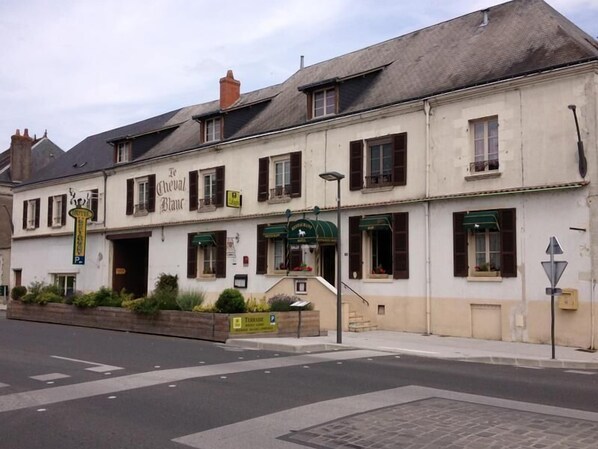 A two-story building with a sign reading "Le Cheval Blanc."