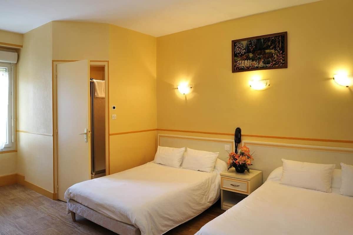 Habitació d'hotel amb dos llits, una tauleta de nit, un quadre a la paret i una porta al bany.