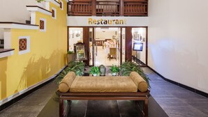 A restaurant with a wooden bench in the center, surrounded by potted plants.
