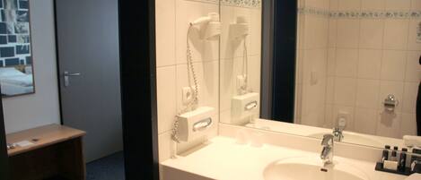 Un baño de hotel con un lavamanos blanco, un espejo y un perchero para toallas.