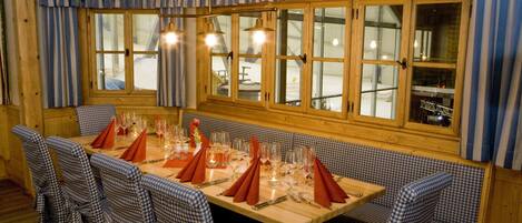 A dining area with a long wooden table set for a meal, surrounded by checkered chairs.