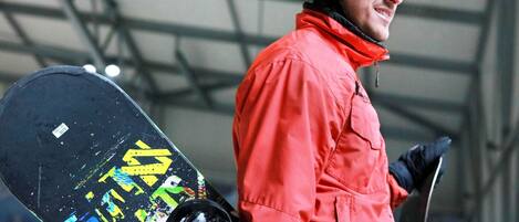 A person in a red jacket holding a snowboard with a colorful design.