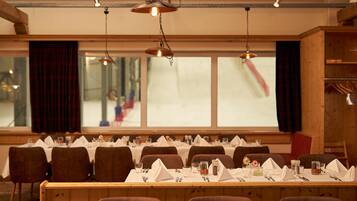 A dining area with tables set for a meal, chairs, and hanging pendant lights.