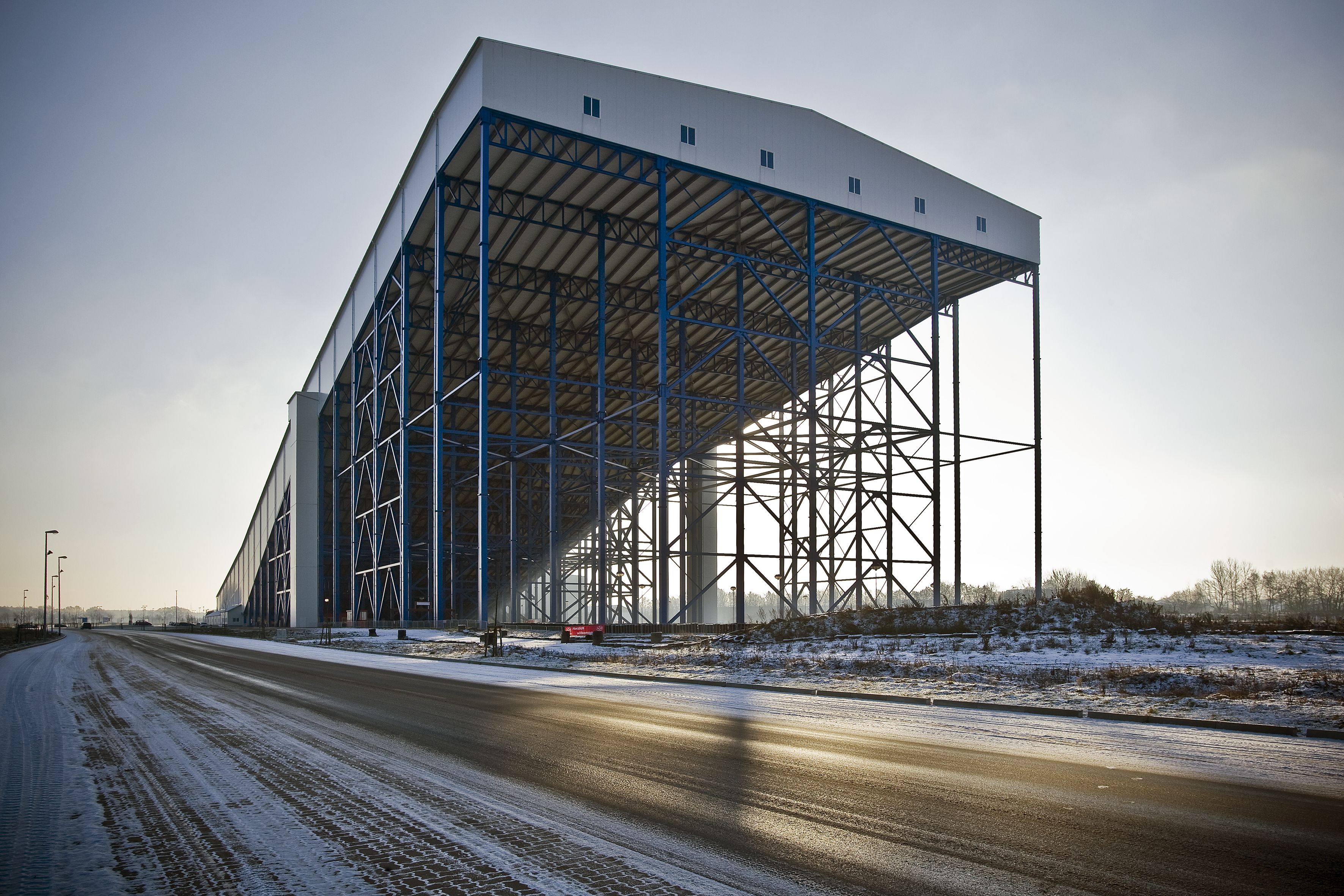 A large industrial building with a metal framework and a covered walkway.