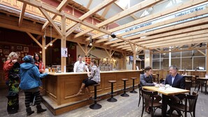 A wooden interior with a bar area, high ceilings, and a view of the outside.