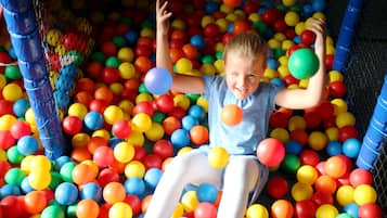 Un niño jugando en un chapoteadero de pelotas de muchos colores.