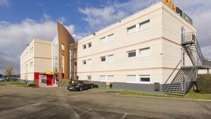 A hotel with a modern design, a parking lot, and a staircase leading to the entrance. - hotelF1 Maurepas (Maurepas)