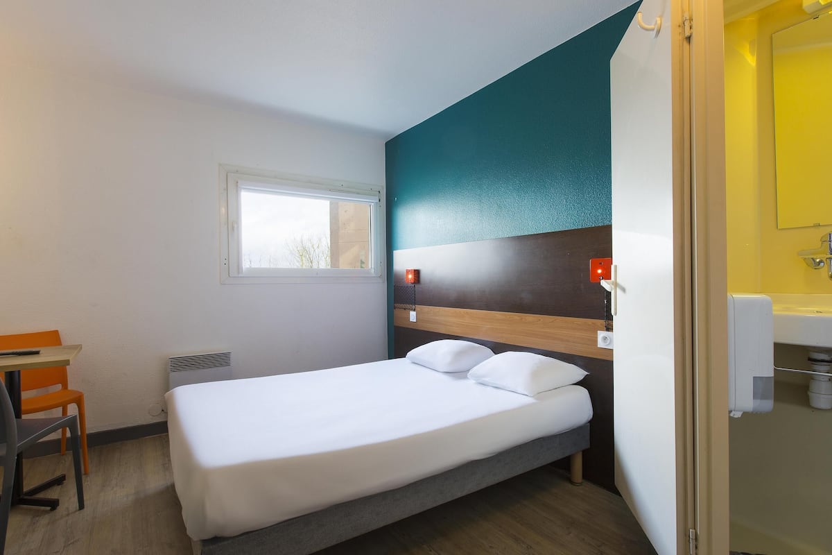 Une chambre d’hôtel comprenant un lit, un bureau, une chaise, une fenêtre et une salle de bain.
