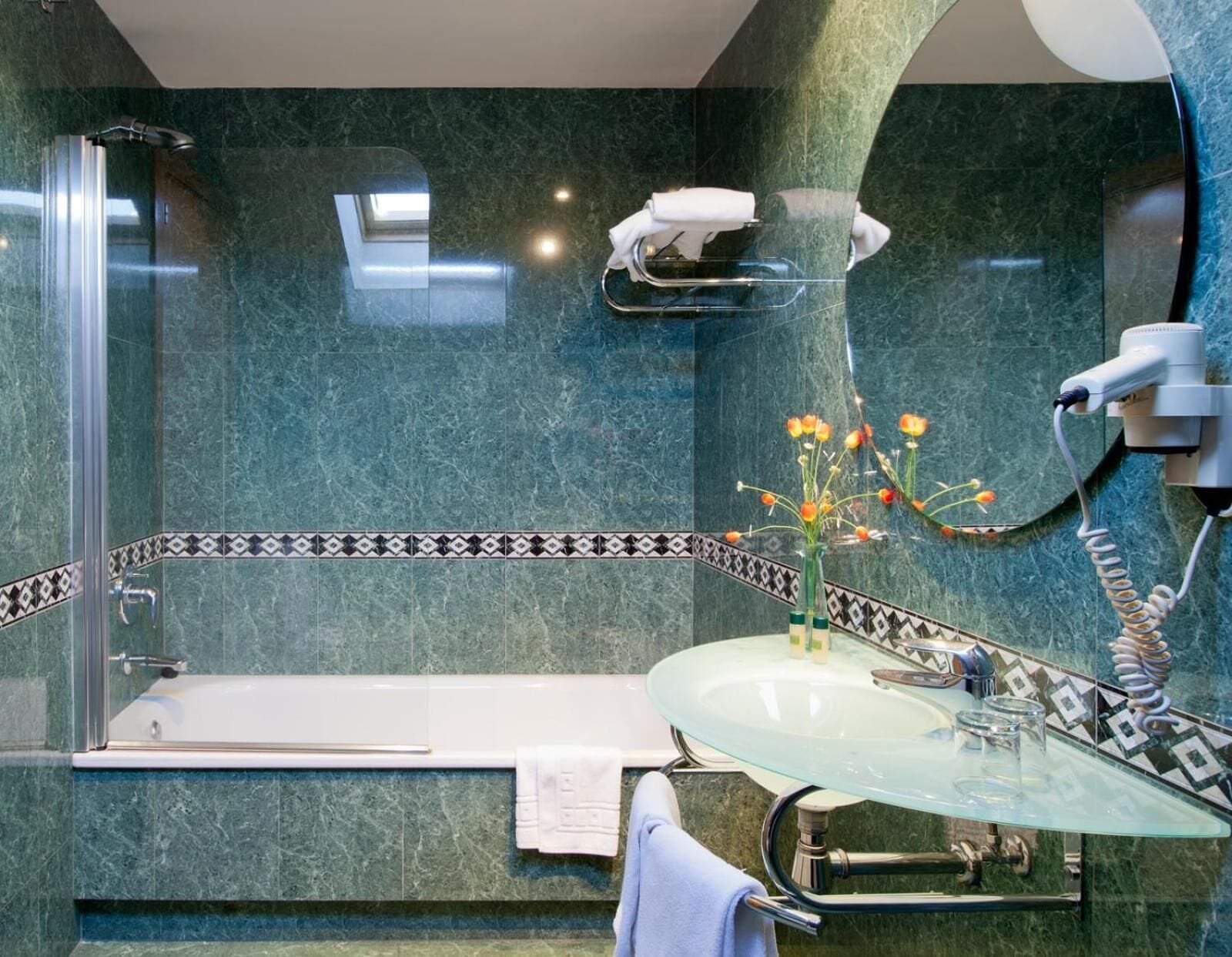 Un baño moderno con lavamanos de vidrio, bañera y ducha.