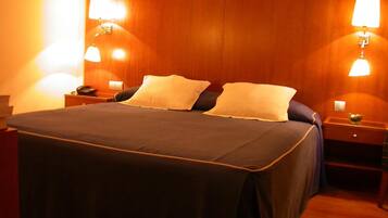 Una habitación de hotel con una cama grande, dos lámparas de noche, un teléfono y una mesita de noche con un frutero.