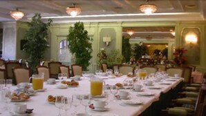 A formal dining room with a long table set for breakfast, surrounded by chairs.