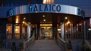 A hotel entrance with a curved facade, a staircase leading up to the entrance, and a sign that reads "GALAICO HOTEL".