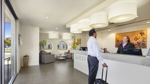 A hotel reception area with a modern design, including a reception desk, seating area, and a large window offering a view of the outdoors. - Quest Mildura (Mildura)