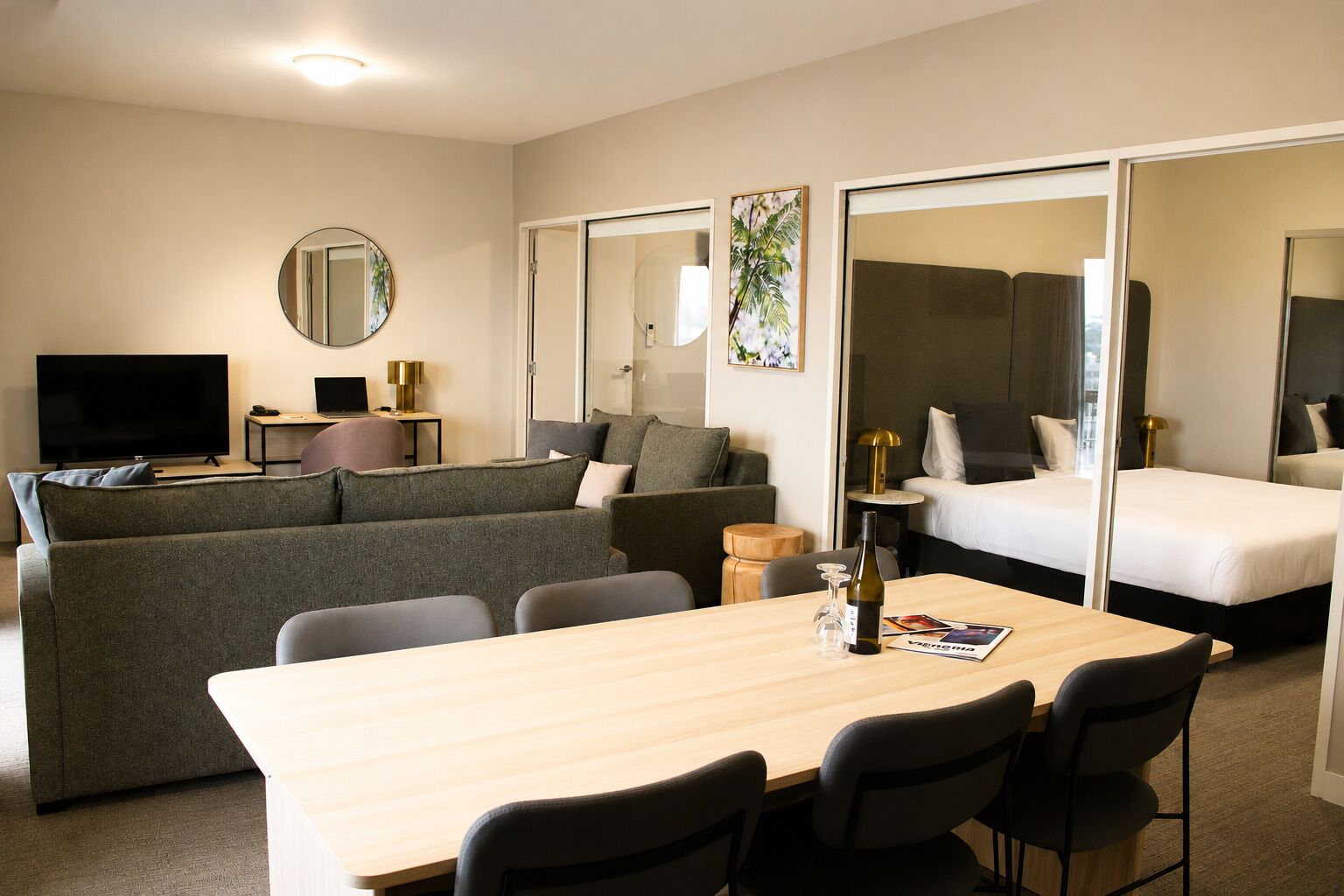 Une chambre d’hôtel équipée d’un canapé, d’un lit, d’une télévision, d’une table avec des chaises et d’un miroir.