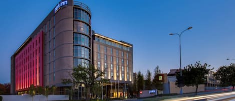 A modern hotel with a curved facade, large windows, and a prominent signage.