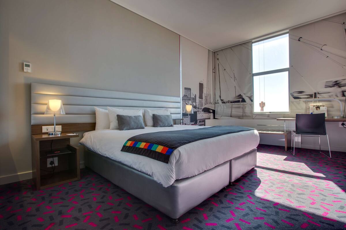 Una habitación de hotel moderna con una cama grande, un escritorio y una silla.