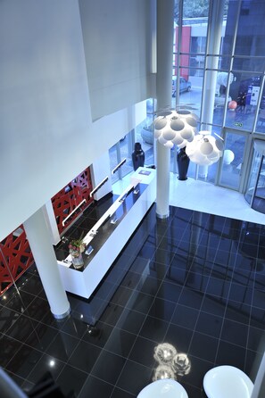 A modern hotel lobby with a reception desk, large windows, and a black-tiled floor. - Park Inn Sandton (Sandton)