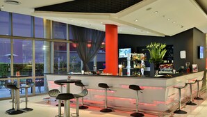 Eine moderne Bar mit einer Theke, Barhocker und einem großen Fenster.