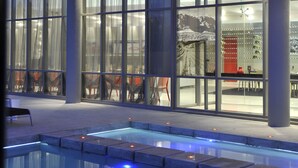 Ein modernes Gebäude mit großen Fenstern, einem Poolbereich und Sitzmöglichkeiten im Freien.