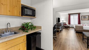 A compact hotel room with a kitchenette, a bed, a desk, and a seating area. - Best Western Moriarty Heritage Inn (Moriarty)