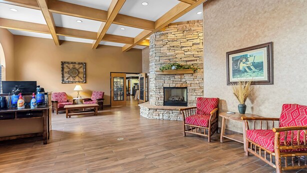 A spacious lobby with a stone fireplace, wooden furniture, and a television. - Best Western Moriarty Heritage Inn (Moriarty)