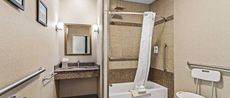 A modern bathroom with a shower, a sink, a mirror, and a toilet with a safety rail.