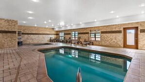 An indoor swimming pool with tiled walls and ceiling, surrounded by lounge chairs and a small table. - Comfort Suites Roswell North (Roswell)