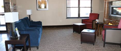 A living room with a blue sofa, a red chair, a small table, and a rug.