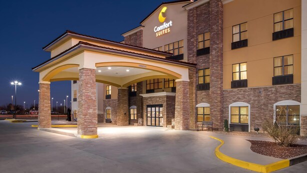 A hotel entrance with a covered area, multiple windows, and a sign reading "Comfort Suites". - Comfort Suites Roswell North (Roswell)