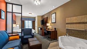 A hotel room with a sofa, desk, chair, and a large bathtub. - Comfort Suites Roswell North (Roswell)