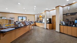A modern hotel lobby with a coffee station, a reception area, and a wall with a coffee-themed sign. - Comfort Suites Roswell North (Roswell)