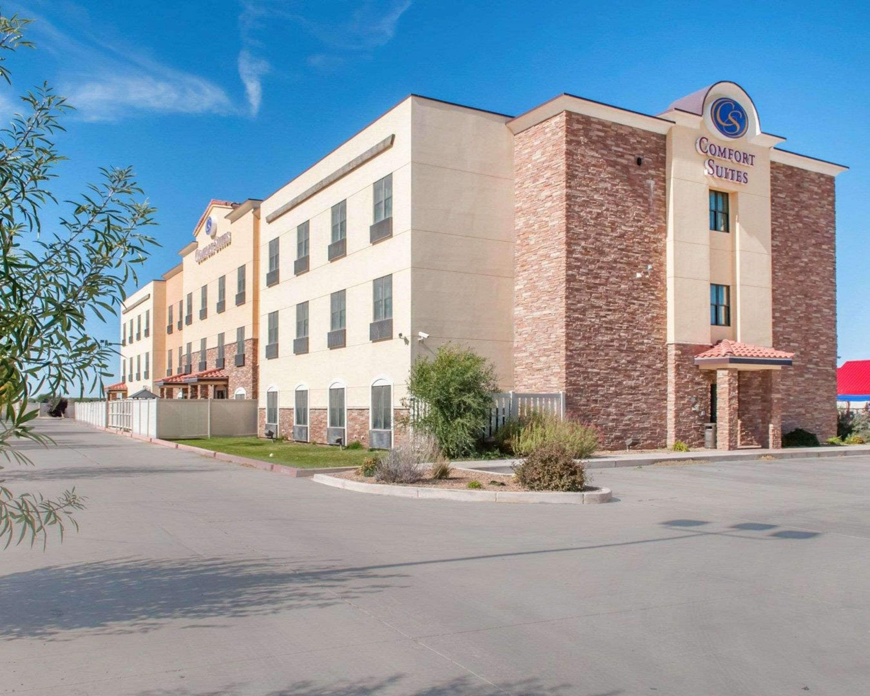 A multi-story hotel with a brick facade and a sign for 'Comfort Suites'.