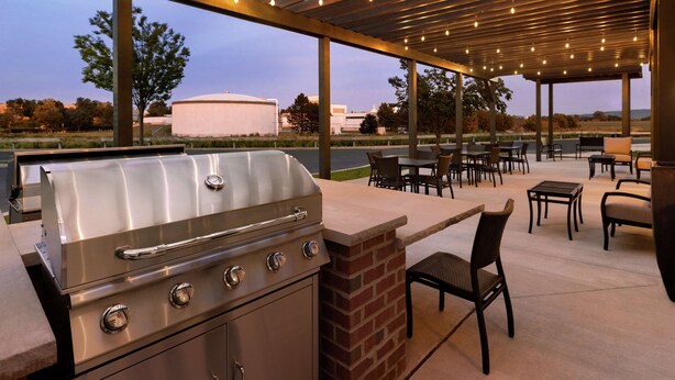 An outdoor patio with a built-in grill, seating area, and a view of the surrounding landscape.