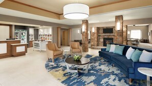 A spacious living area with a blue sofa, beige armchairs, a coffee table, and a stone fireplace.