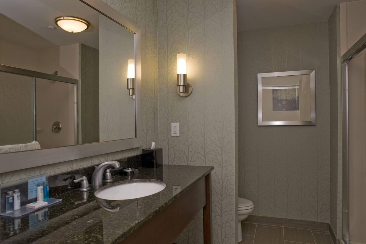 A bathroom with a sink, mirror, and two wall-mounted lights.