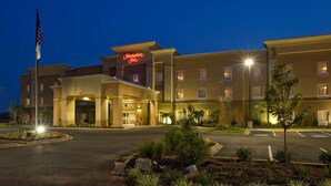A Hampton Inn hotel with a well-lit entrance, a flagpole, and a landscaped area with plants. - Hampton Inn Anderson/ Alliance Business Park (Anderson)