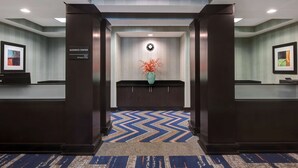 A business center with a reception desk, a clock, and a vase with red flowers. - Hampton Inn Anderson/ Alliance Business Park (Anderson)