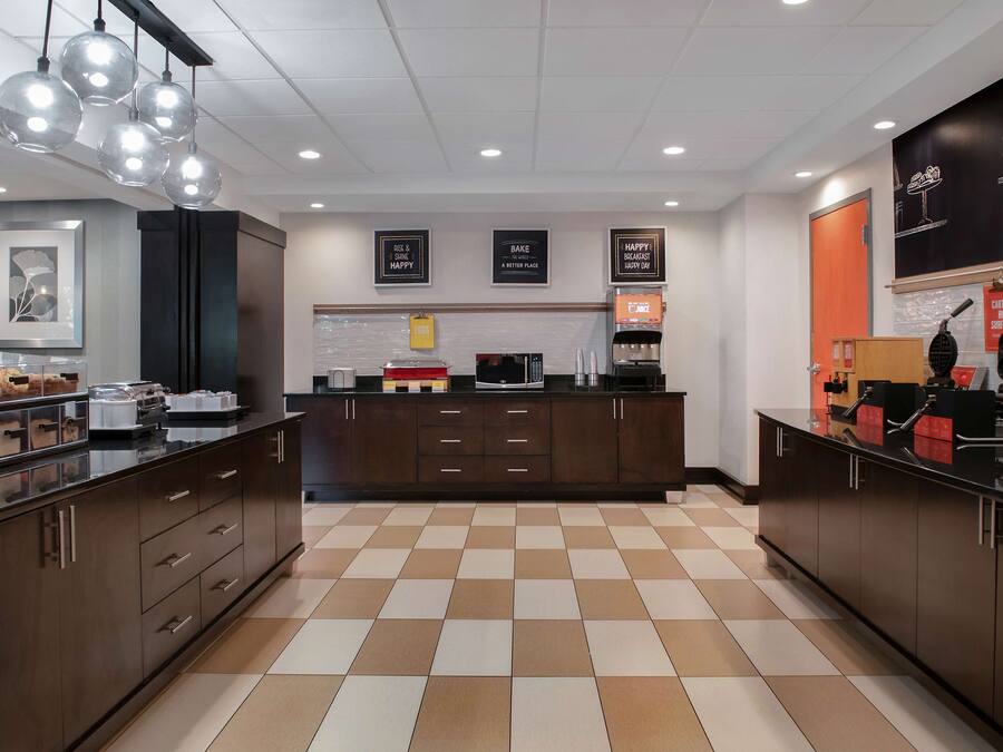 A modern kitchen with checkered flooring, dark cabinetry, and a central island.